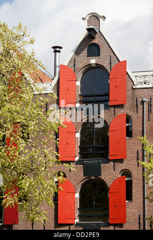 Maison historique avec des volets rouges et pignon triangulaire, converti de l'ancien bâtiment de l'entrepôt, Amsterdam, Pays-Bas. Banque D'Images