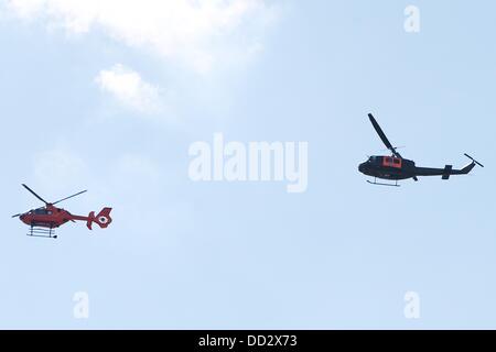 Les gens regardent le SAR Bell UH-1D'hélicoptère de l'Armée de l'air, surnommé 'Anneliese' (R), et l'Christoph 29 CE 135 hélicoptères de la défense civile voler en face de l'Hôpital Militaire de Hambourg, Allemagne, 24 août 2013. Les pilotes de sauvetage des Forces armées allemandes de célébrer leur 40e anniversaire. Photo : MALTE CHRÉTIENS Banque D'Images