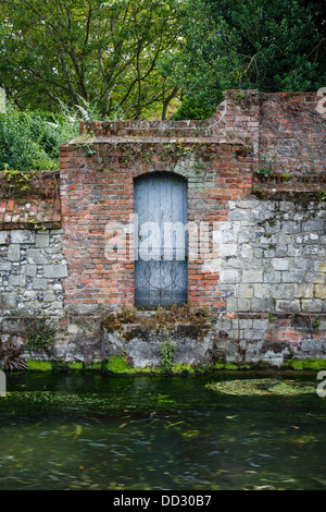 Mur de pierre ancienne et porte sur une rive du fleuve à Winchester, Hampshire, Royaume-Uni Banque D'Images