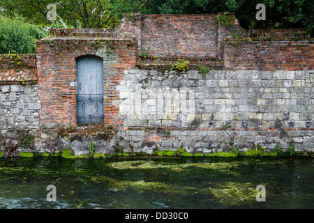 Mur de pierre ancienne et porte sur une rive du fleuve à Winchester, Hampshire, Royaume-Uni Banque D'Images