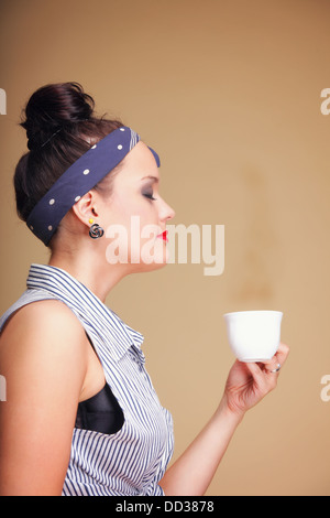 Belle fille de boire du thé ou du café. Tasse de boisson chaude fond brun Banque D'Images