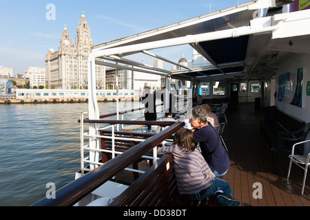 Les passagers de l'emblématique ferry Mersey regardez les trois grâces sur le front de mer historique de Liverpool à Liverpool, Banque D'Images