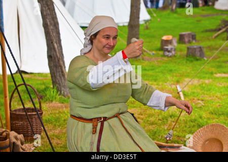 Femme en costume médiéval filer, participant à la cité médiévale de Fayre Tatton Park, Cheshire, Angleterre. Banque D'Images