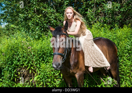 Jeune jolie fille à cheval dans la forêt Banque D'Images