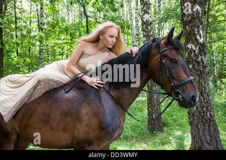 Jeune jolie fille à cheval dans la forêt Banque D'Images