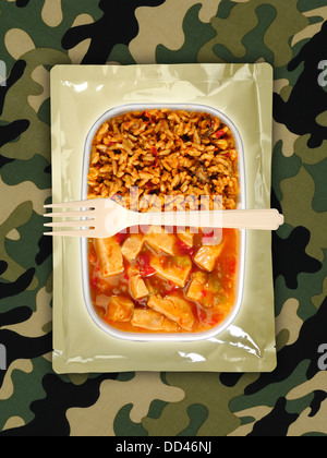 Des rations alimentaires militaires ou MRE repas prêt à manger sur un fond camouflé. Ouvrir les paquets avec des ustensiles en plastique. Banque D'Images