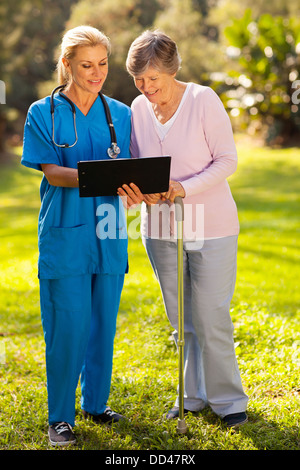 Smiling nurse montrant senior patient ses résultats de tests médicaux à l'extérieur Banque D'Images