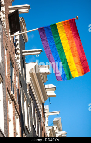 De couleur arc-en-ciel drapeau flotte à partir d'une rangée de maisons typiques du canal à Amsterdam pendant l'émancipation LGBT Gay Pride, manifestation. Banque D'Images