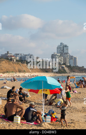 Détente en famille sur la plage avec une tour immobilier buildibg en arrière-plan. Givat Alyah beach. Jaffa. Israël. Banque D'Images