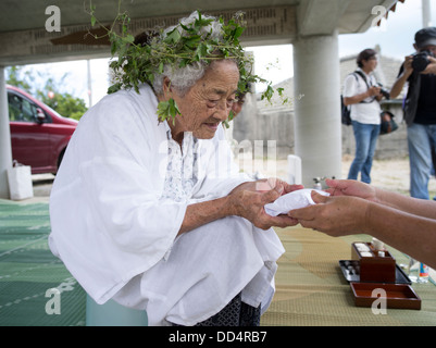 96 ans Kaneshi Fusae wearing wreath d botanzuru Unjami ryukyu au Festival sur Kouri Island, Okinawa compte tenu des gâteaux de riz mochi Banque D'Images