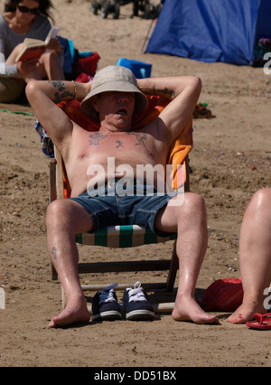 L'homme endormi dans une chaise longue sur la plage, Weymouth, Dorset, UK 2013 Banque D'Images