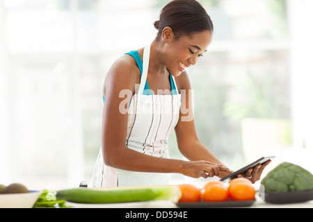 Jolie femme africaine à la recherche d'une recette sur Internet à l'aide de tablet computer Banque D'Images