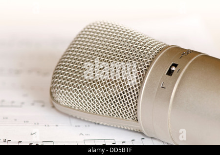 Close-up d'un microphone à condensateur couché sur un livre de musique. Banque D'Images