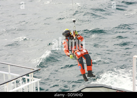 L'hélicoptère de recherche et sauvetage de la Garde côtière sur l'exercice d'un treuil d'équipage sur un traversier dans le Minch, près de l'Outer Hebrides Banque D'Images