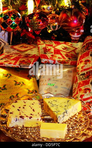 Blue Stilton, Wensleydale avec canneberges et fromages cheddar sur une plaque de verre avec des cadeaux de Noël et à l'arrière de l'arbre Banque D'Images