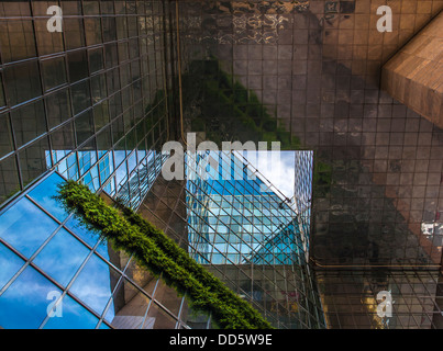 Un bâtiment moderne de verre avec reflet du ciel bleu et la verdure des plantes. Banque D'Images