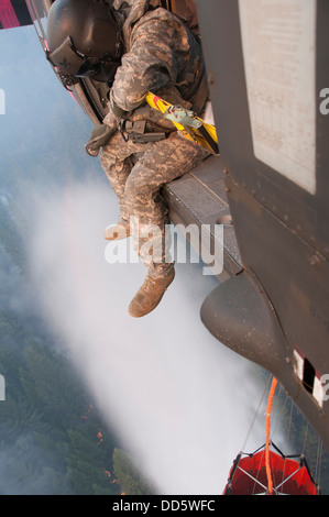 Le Sgt. Chris Boni, chef d'équipage de la Garde nationale de Californie, 1-140ème bataillon de l'Aviation (Air Assault) sur la base de formation conjointe de Los Alamitos (JFTB), les rejets de l'eau sur la tête arrosant le rim fire ci-dessous près de Yosemite National Park. Le Sapin Rim Banque D'Images