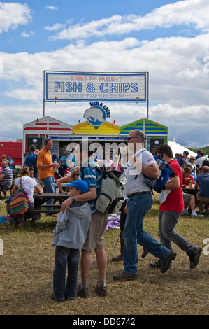 Vue verticale de gens debout par un poisson et chip stand à un festival au soleil. Banque D'Images