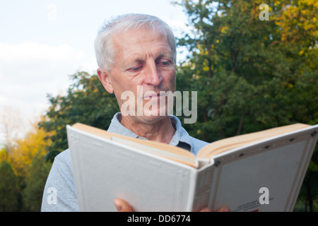 Vieil homme maigre livre de lecture en plein air dans le parc Banque D'Images