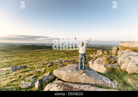 Vintage femme debout sur le dessus de la colline avec des bras outstreched et looking at view Banque D'Images