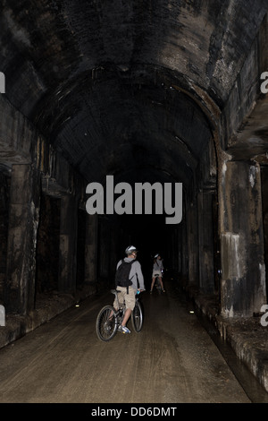 Les cyclistes entrant dans un tunnel noir avec lampes Banque D'Images