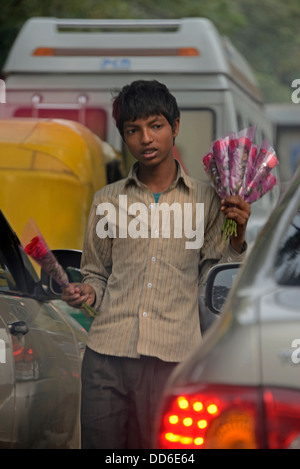 Un jeune garçon à la vente de fleurs aux automobilistes pris dans le trafic à Delhi, Inde Banque D'Images