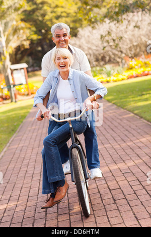 Cheerful senior couple à vélo dans un parc Banque D'Images