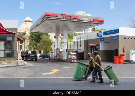 Dakar, Sénégal. Station d'essence moderne, deux nettoyeurs de rue en marche. Banque D'Images