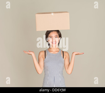 Jeune femme heureuse reste boîte en carton sur la tête. Banque D'Images