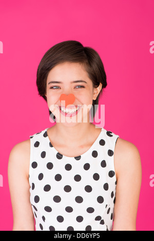 Les jeunes de rire et insouciante avec femme multiraciale un cœur rouge sur son nez Banque D'Images