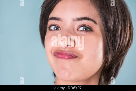 Young woman making funny face serrant son visage contre la fenêtre en verre Banque D'Images