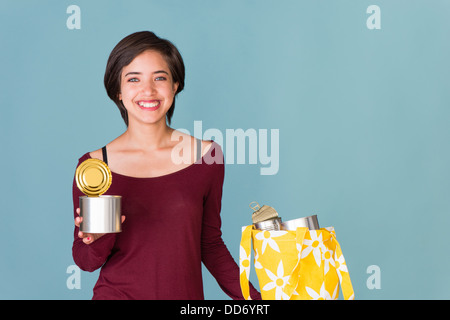 Portrait of smiling young woman multiraciale le recyclage de boîtes en métal Banque D'Images