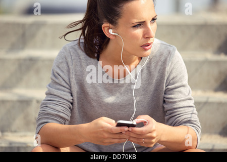 Jeunes femmes athlètes se reposer et écouter de la musique mp3 en plein air Banque D'Images