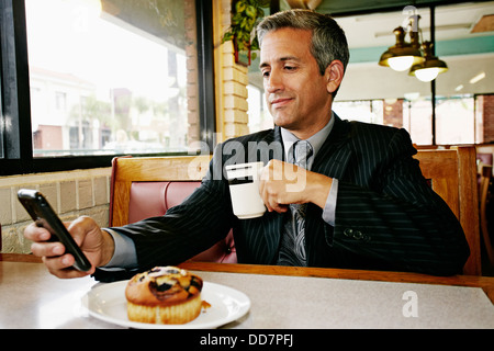 Hispanic businessman using cell phone in restaurant Banque D'Images