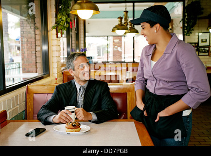 Hispanic waitress talking to businessman in restaurant Banque D'Images