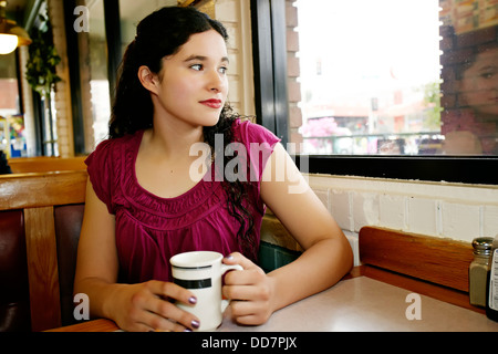 Mixed Race woman having coffee in restaurant Banque D'Images