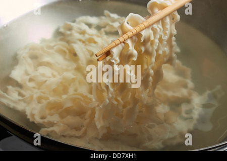 Faire bouillir les nouilles chinoises dans un wok en acier Banque D'Images