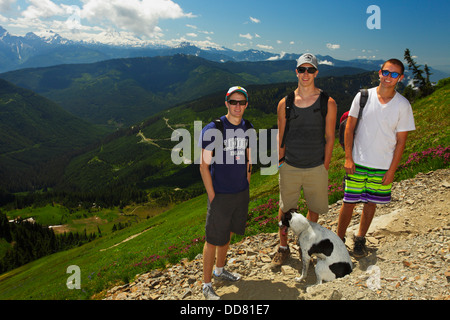 Trois adolescents et chien près de Mont Cheam dans les hautes prairies alpines en été et en Colombie-Britannique, Canada. Banque D'Images