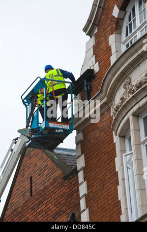 Les entrepreneurs sur la plate-forme d'accès haute sécurité faire un bâtiment après avoir été endommagé par la foudre dans la ville de York England UK Banque D'Images