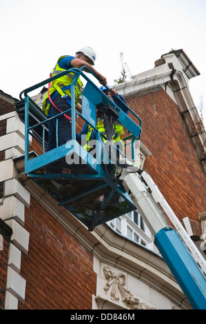 Les entrepreneurs sur la plate-forme d'accès haute sécurité faire un bâtiment après avoir été endommagé par la foudre dans la ville de York England UK Banque D'Images