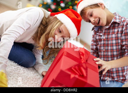 Portrait of happy frères et sœurs à l'intérieur de big red sur coffret soirée de Noël Banque D'Images