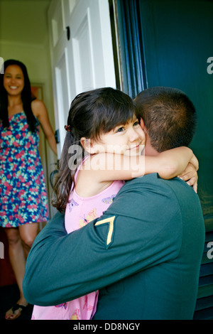 Girl hugging soldier father at door Banque D'Images