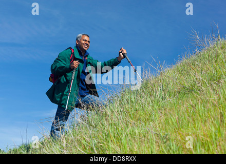 Mixed Race man hiking on grassy hill Banque D'Images