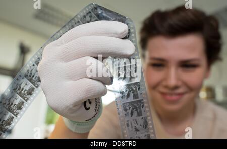 Membre du personnel Miriam Piorno examine une bobine de film du film "Der Himmel auf Erden" (lit. Le paradis sur terre) à partir de 1935, dans le département de la restauration de films et de la conservation à la German Federal Film Archive à Berlin, Allemagne, 12 août 2013. Le directeur du département pour la restauration et la conservation du film s'inquiète de l'état de désolation de certains des dépôts de films qui sont répartis dans des installations différentes à différents endroits. Les négociations sont en cours depuis des années au sujet d'un nouveau film de l'installation centrale pour la conservation et l'archivage dans Berlin, près de Berlin. Photo Banque D'Images