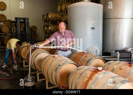 USA, Washington, Outlook. John Zimmerman, vigneron pour Caves à Tefft utilise un topping wand pour remplir un tonneau de vin. Banque D'Images