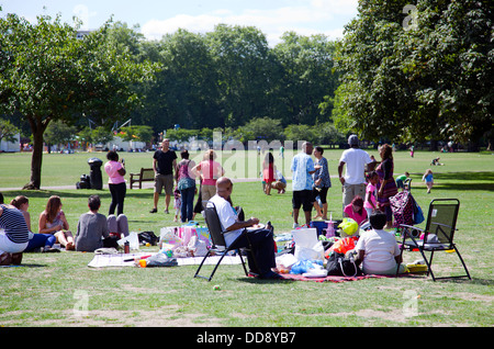 Des groupes de personnes sur l'herbe sur Battersea Park en été - London UK Banque D'Images