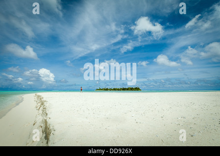 Les Îles Cook, Aitutaki Lagoon, femme marche sur le désert de sable blanc de l'île de miel avec atoll Maina en arrière-plan Banque D'Images