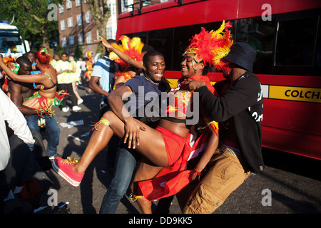 Deux mecs pour une danseuse et danse avec eux que la parade se déplace le long de la rue. Banque D'Images
