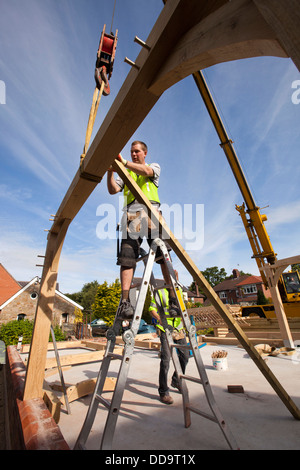 L bâtiment maison, les travailleurs en chêne vert construction bâtiment encadré avec l'aide de grue Banque D'Images