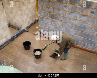 L bâtiment maison, construire les maisons, woman sweeping plancher propre avec pelle et brosse pour garder propre site Banque D'Images